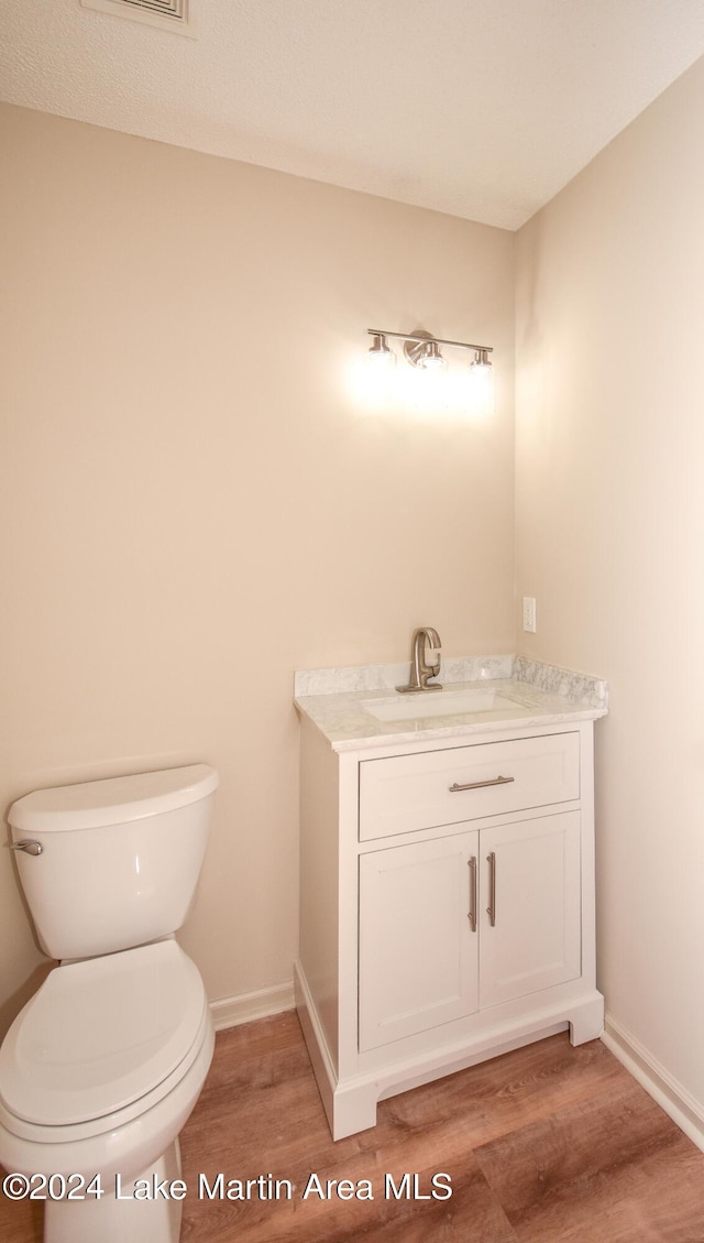 bathroom with hardwood / wood-style floors, toilet, and vanity