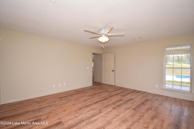 spare room with light wood-type flooring, a textured ceiling, and ceiling fan