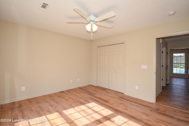 unfurnished bedroom with light wood-type flooring, ceiling fan, and a closet