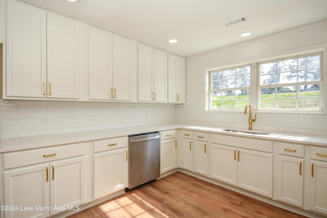 kitchen featuring white cabinets, light hardwood / wood-style floors, sink, backsplash, and stainless steel dishwasher