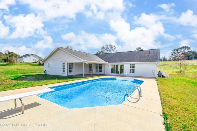 view of swimming pool featuring a yard, a diving board, and a patio