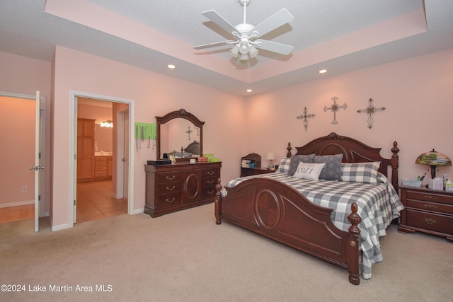 carpeted bedroom featuring ensuite bathroom, ceiling fan, and a raised ceiling