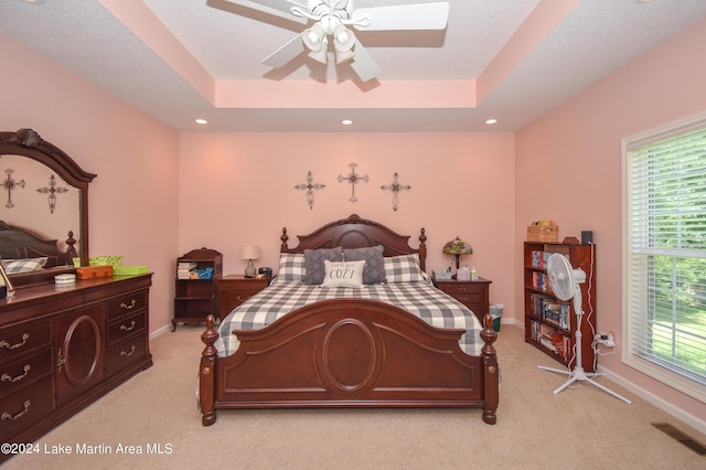 carpeted bedroom featuring ceiling fan and a raised ceiling
