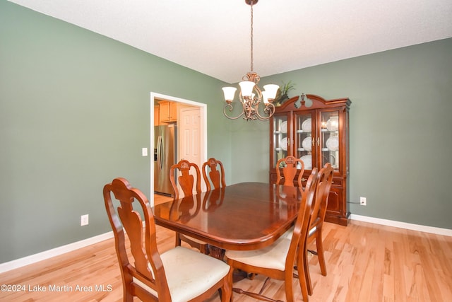 dining space featuring light wood-type flooring and a notable chandelier
