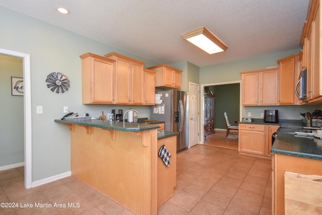 kitchen with sink, stainless steel appliances, kitchen peninsula, a textured ceiling, and light tile patterned floors