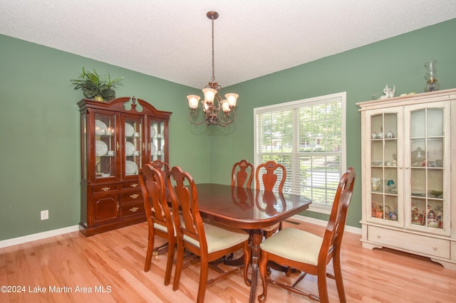 dining space featuring a notable chandelier, a textured ceiling, and light hardwood / wood-style flooring