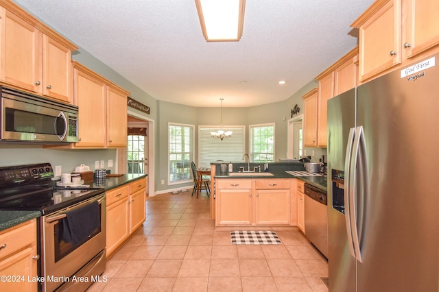 kitchen featuring light brown cabinetry, stainless steel appliances, sink, decorative light fixtures, and a notable chandelier