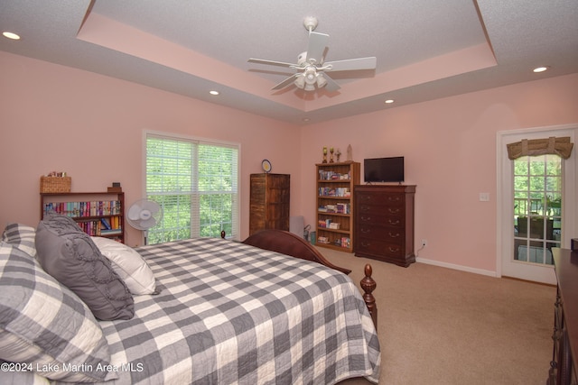carpeted bedroom with a tray ceiling and ceiling fan