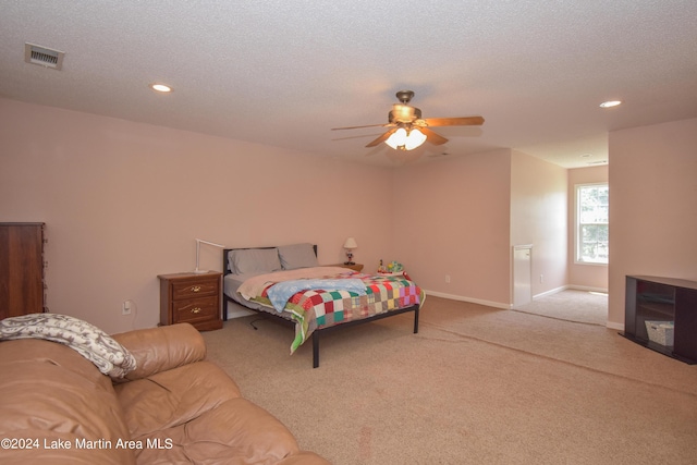 bedroom with ceiling fan, light colored carpet, and a textured ceiling