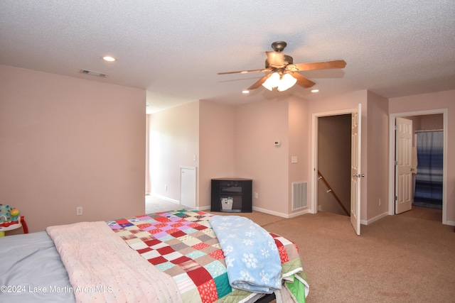 carpeted bedroom featuring ceiling fan and a textured ceiling