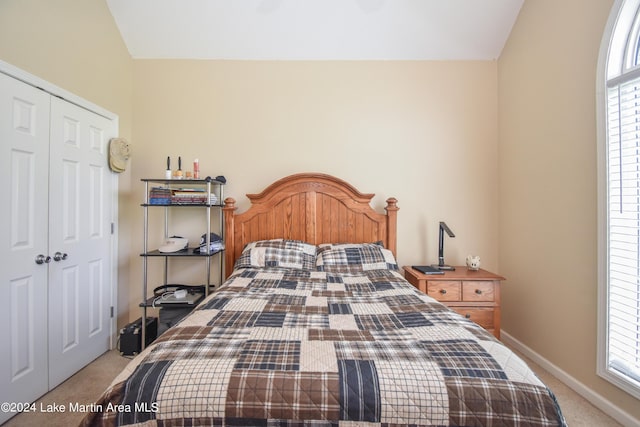 carpeted bedroom with multiple windows, a closet, and lofted ceiling