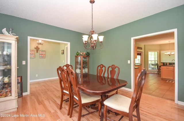 dining room with sink, light hardwood / wood-style flooring, and a chandelier