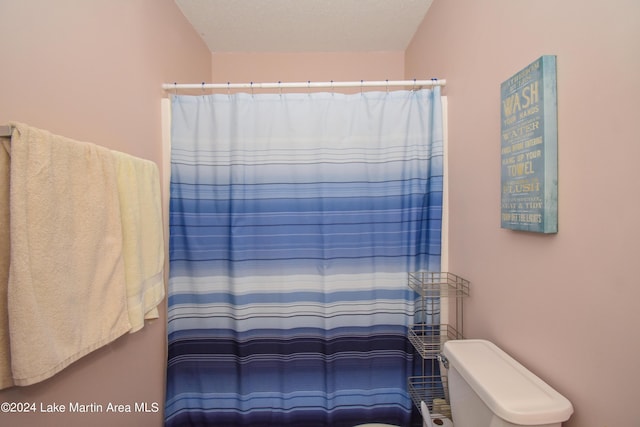 bathroom with toilet, a textured ceiling, and walk in shower