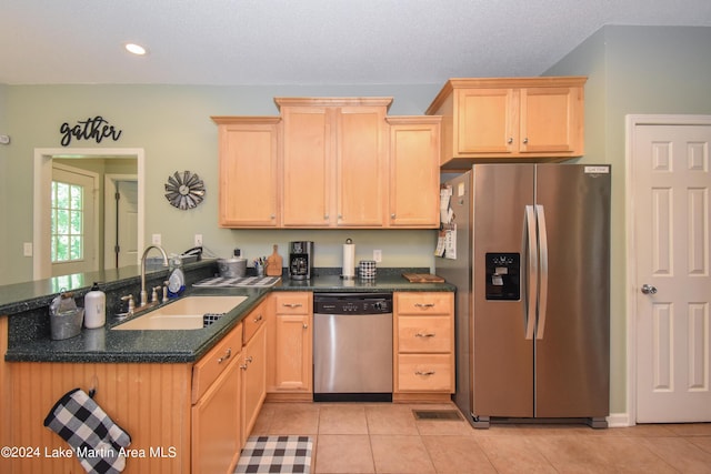 kitchen with sink, kitchen peninsula, light brown cabinetry, light tile patterned floors, and appliances with stainless steel finishes