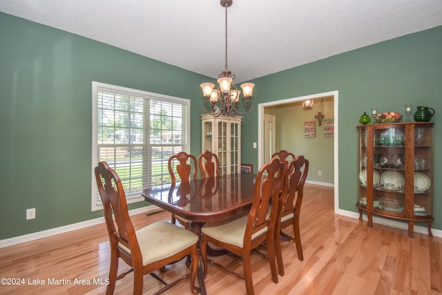 dining area featuring a textured ceiling, light wood-type flooring, and a notable chandelier