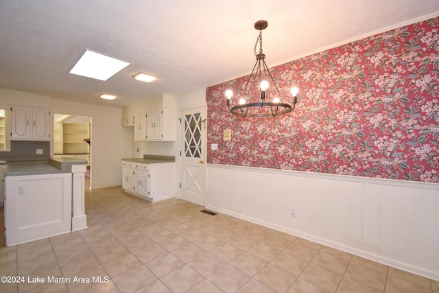 unfurnished dining area with a skylight and a chandelier