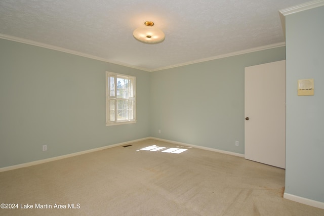 empty room featuring a textured ceiling, light colored carpet, and crown molding