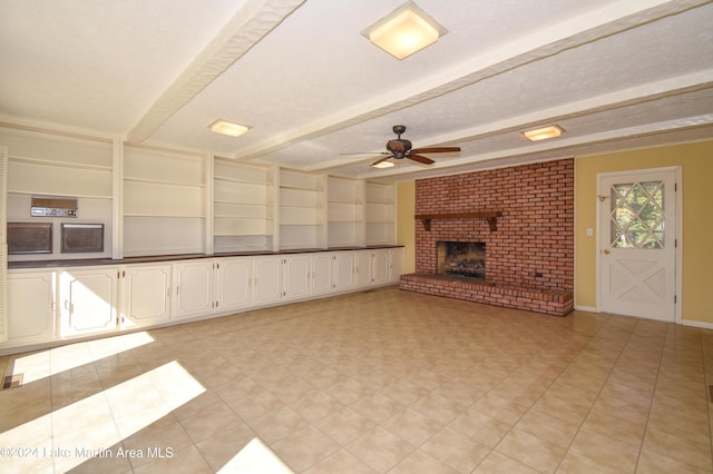 unfurnished living room featuring beam ceiling, ceiling fan, a brick fireplace, built in features, and a textured ceiling