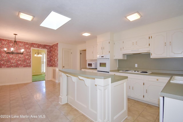 kitchen with white appliances, an inviting chandelier, white cabinets, a kitchen island, and hanging light fixtures