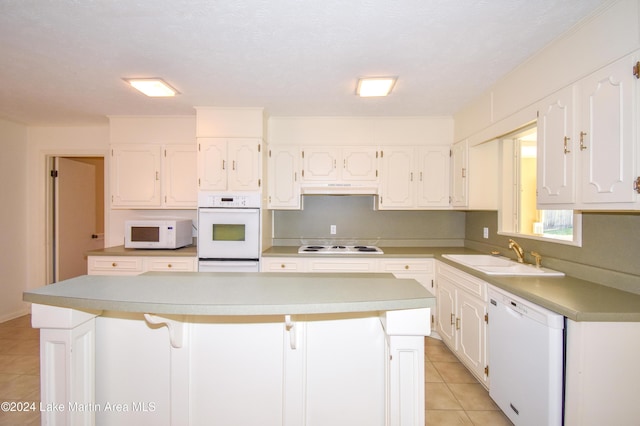 kitchen with white cabinets, a kitchen island, white appliances, and sink