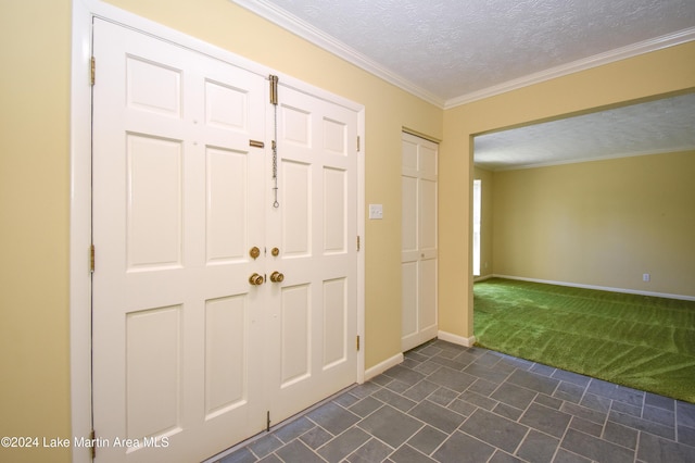 entrance foyer with dark carpet, a textured ceiling, and ornamental molding