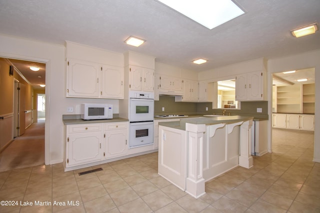 kitchen featuring white cabinetry, white appliances, and a textured ceiling