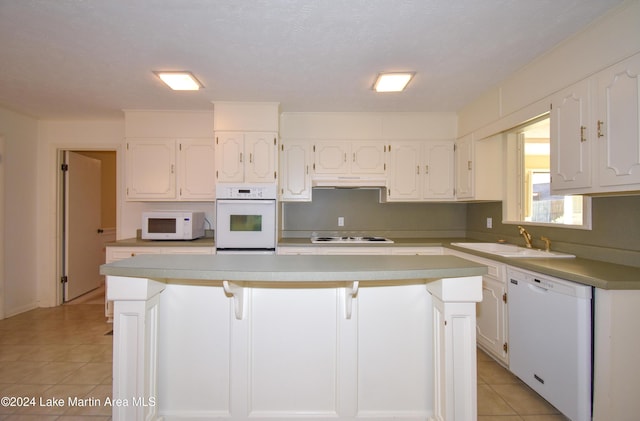 kitchen with white cabinets, a center island, white appliances, and sink