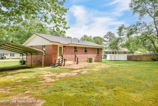 rear view of property with a detached carport, a lawn, brick siding, and fence