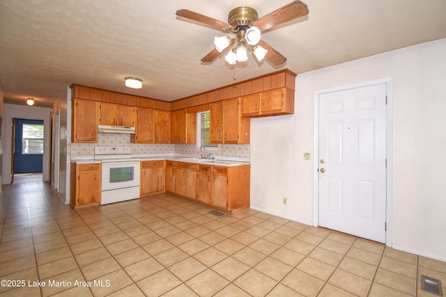 kitchen with electric range, under cabinet range hood, a sink, and light countertops