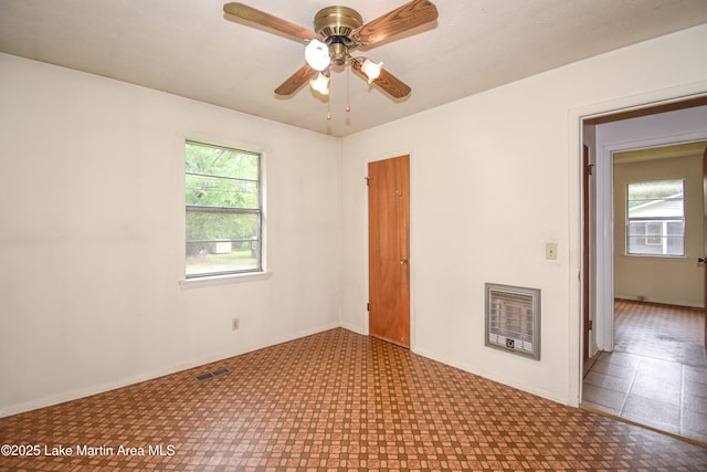 empty room with visible vents, tile patterned floors, baseboards, and ceiling fan