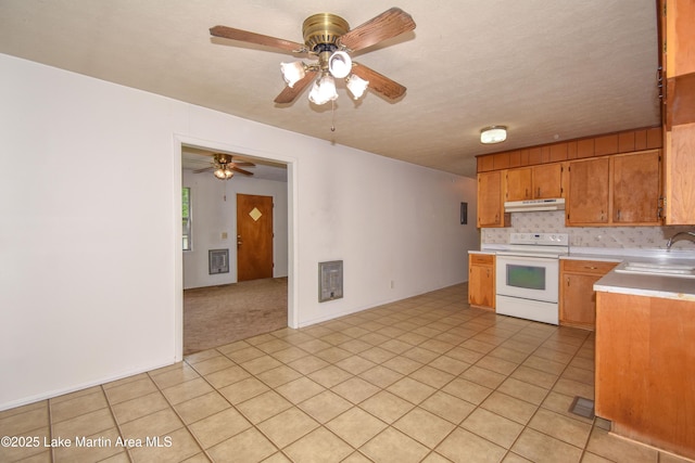 kitchen with a sink, ceiling fan, light countertops, electric range, and under cabinet range hood