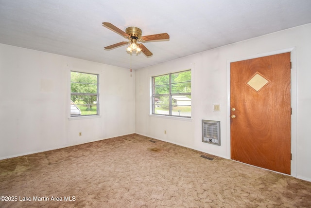 interior space featuring a wealth of natural light, carpet flooring, heating unit, and visible vents