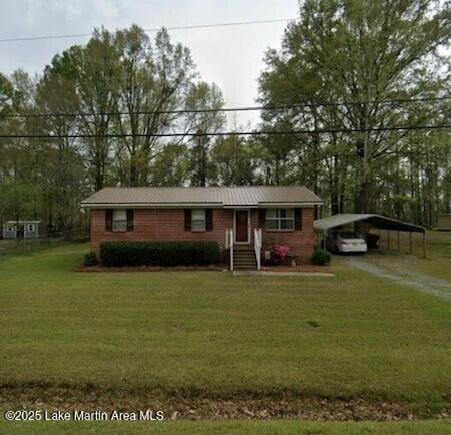 ranch-style home featuring a carport, dirt driveway, and a front lawn