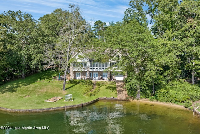 back of property with a lawn and a water view