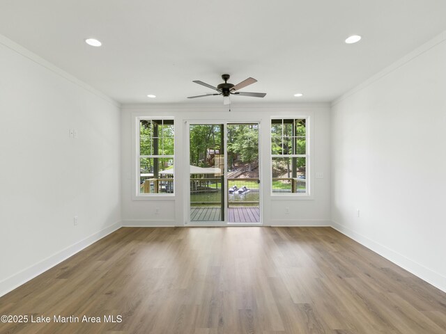 unfurnished room featuring baseboards, plenty of natural light, wood finished floors, and crown molding