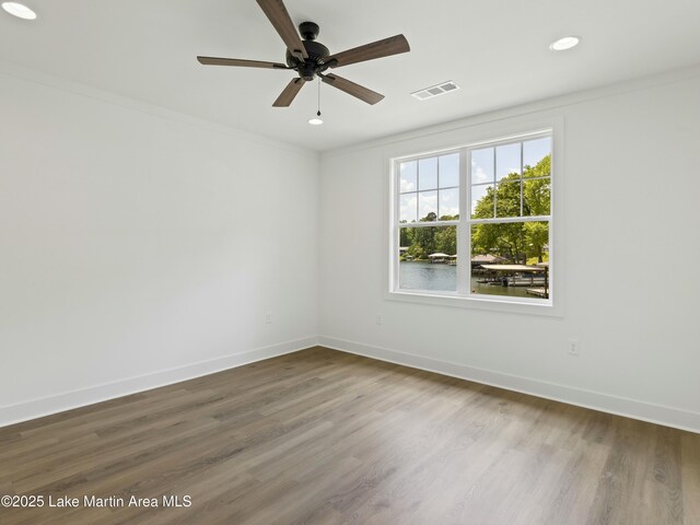 spare room with baseboards, crown molding, visible vents, and wood finished floors