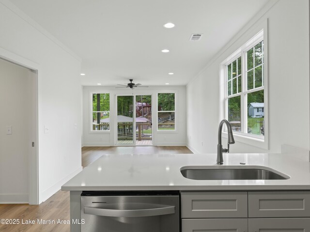 kitchen with a sink, gray cabinets, stainless steel dishwasher, and light countertops