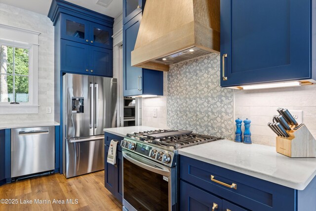116 Water Oak Ln, Jacksons Gap, AL 36861 - kitchen with blue cabinets, appliances with stainless steel finishes, custom exhaust hood, and backsplash