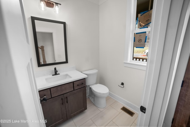 half bath with tile patterned flooring, visible vents, baseboards, toilet, and vanity