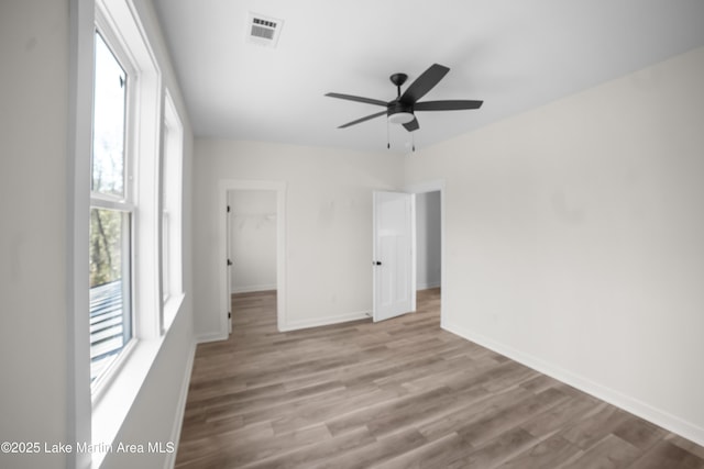 unfurnished room featuring ceiling fan, visible vents, baseboards, and wood finished floors