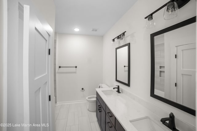 full bath with a sink, baseboards, toilet, and double vanity