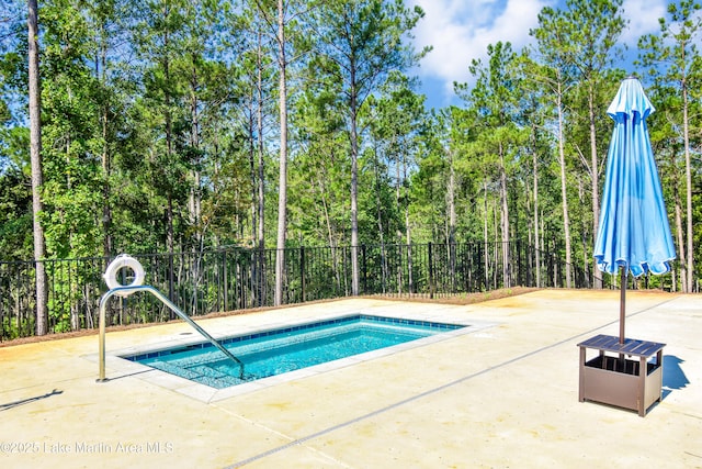 view of swimming pool featuring a patio and fence