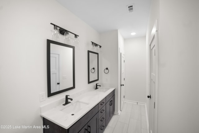 bathroom with double vanity, visible vents, baseboards, and a sink