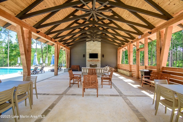 view of patio / terrace featuring outdoor dining space, a ceiling fan, an outdoor pool, and an outdoor stone fireplace