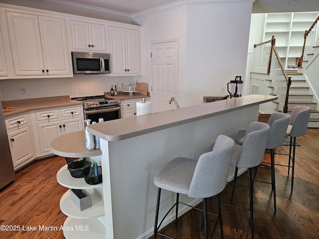 67 Lakeview Dr Unit 10H, Alexander City, AL 35010 - kitchen featuring stainless steel appliances, crown molding, open shelves, white cabinets, and a kitchen bar