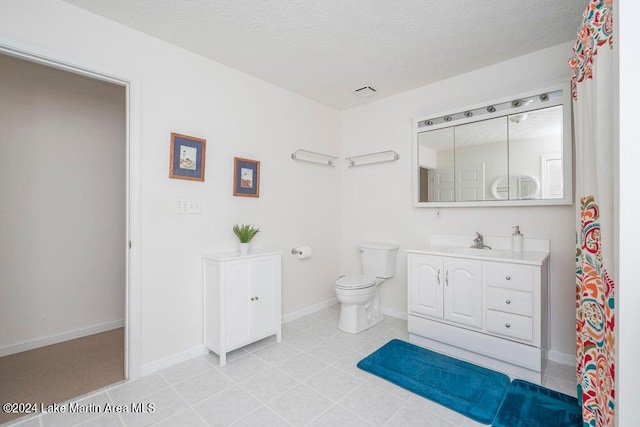 bathroom featuring vanity, a textured ceiling, toilet, and tile patterned flooring