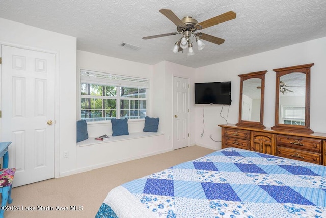 carpeted bedroom with ceiling fan and a textured ceiling