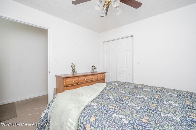 bedroom with ceiling fan, a closet, light colored carpet, and a textured ceiling