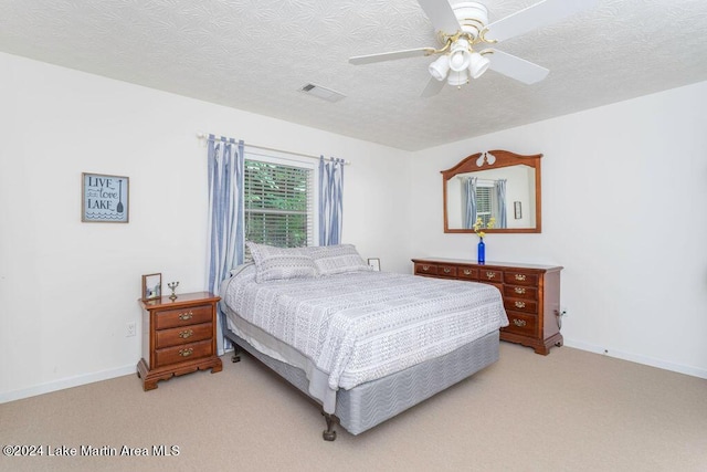 bedroom featuring a textured ceiling, ceiling fan, and light carpet