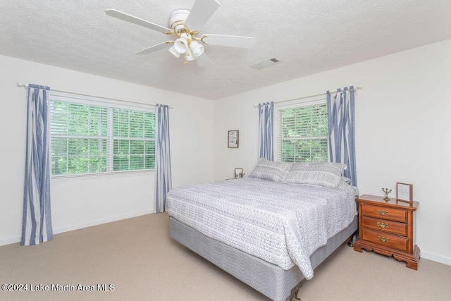 bedroom featuring a textured ceiling, ceiling fan, and light carpet